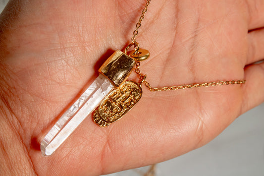 Umbría. Collar con punta de cuarzo blanco y dije oval con símbolos de buena fortuna