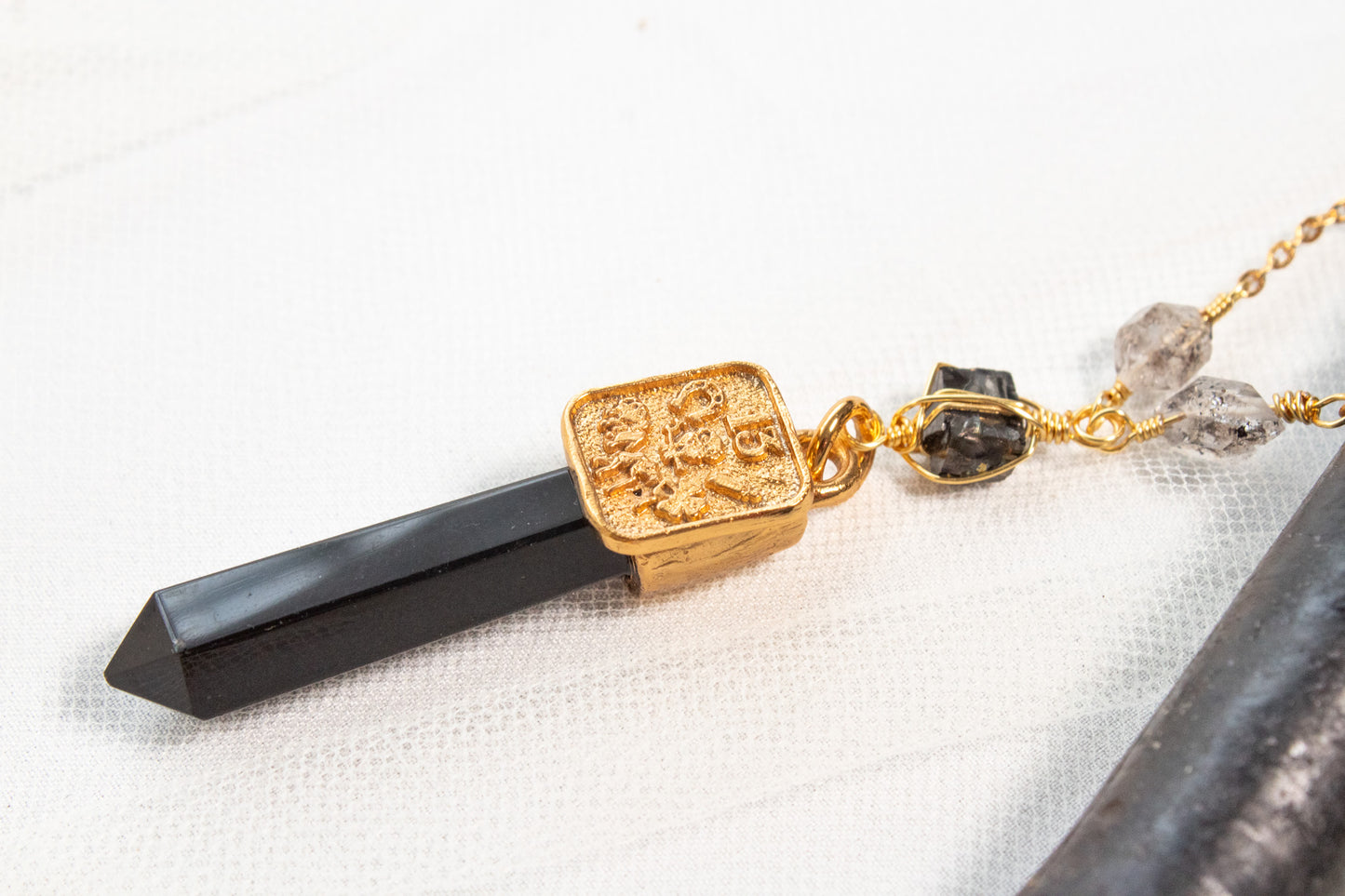 Bastión. Collar con punta de obsidiana, shungita, cuarzo herkimer y símbolos de buena fortuna