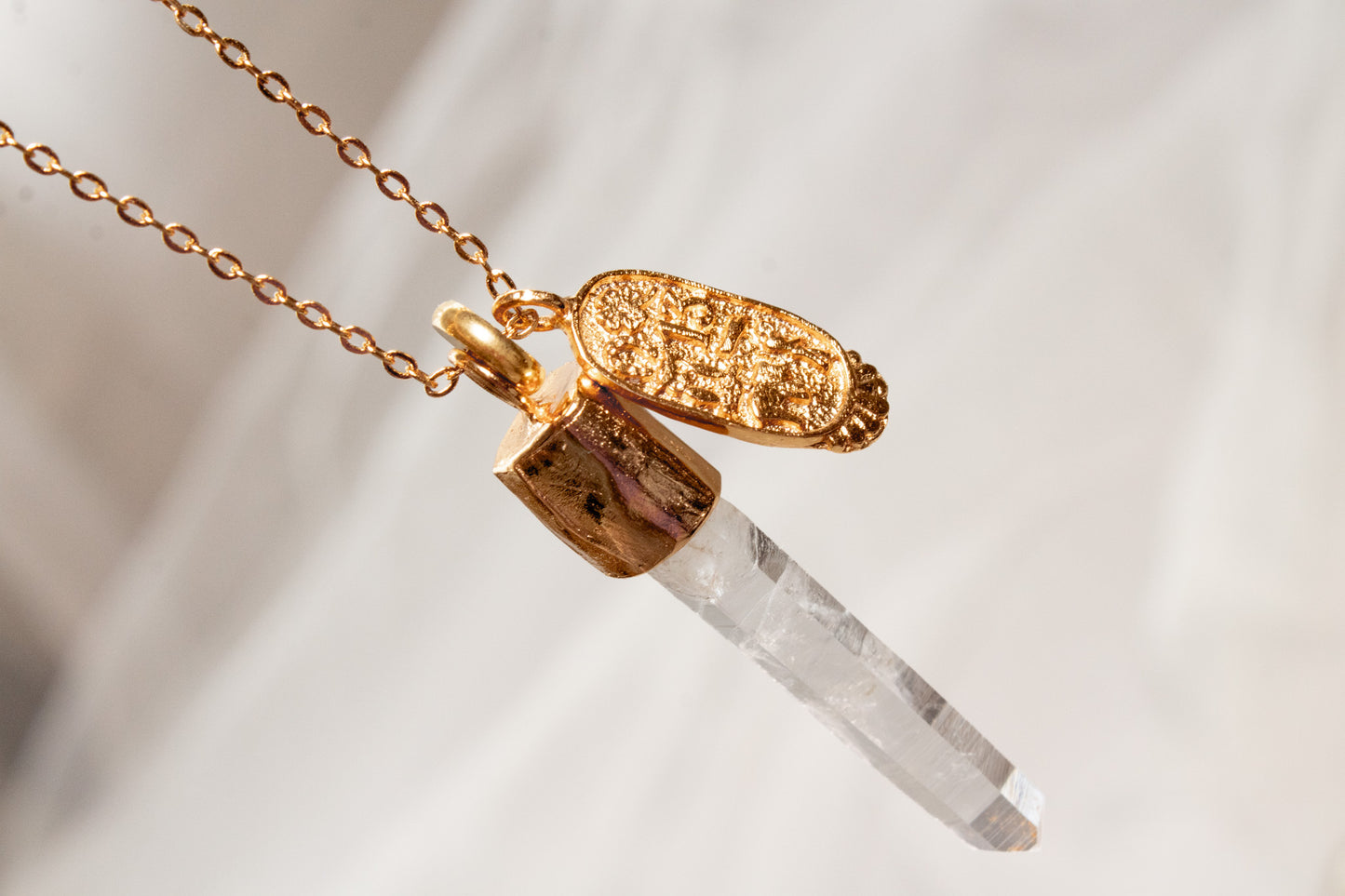 Umbría. Collar con punta de cuarzo blanco y dije oval con símbolos de buena fortuna